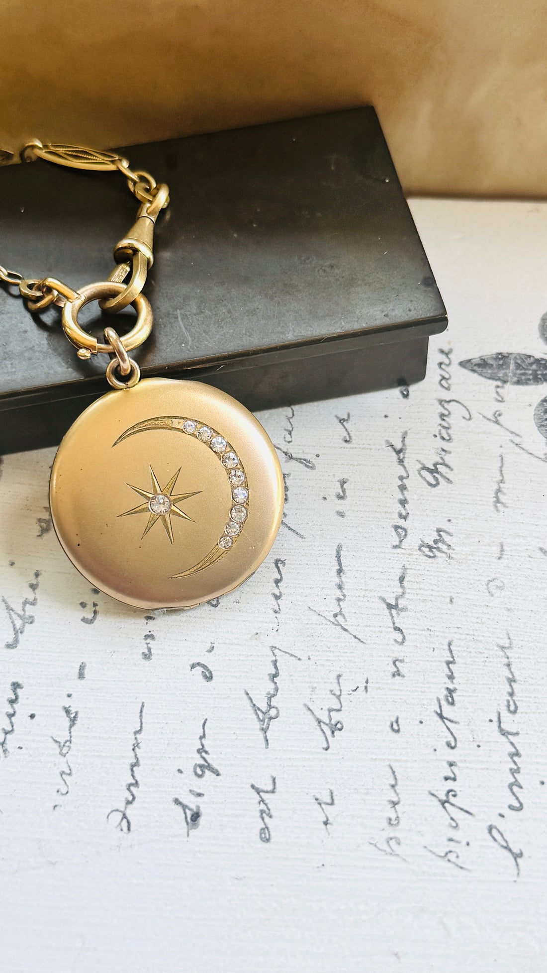 Victorian crescent moon locket paired with an antique French ORIA watch chain, styled on handwritten French paper.