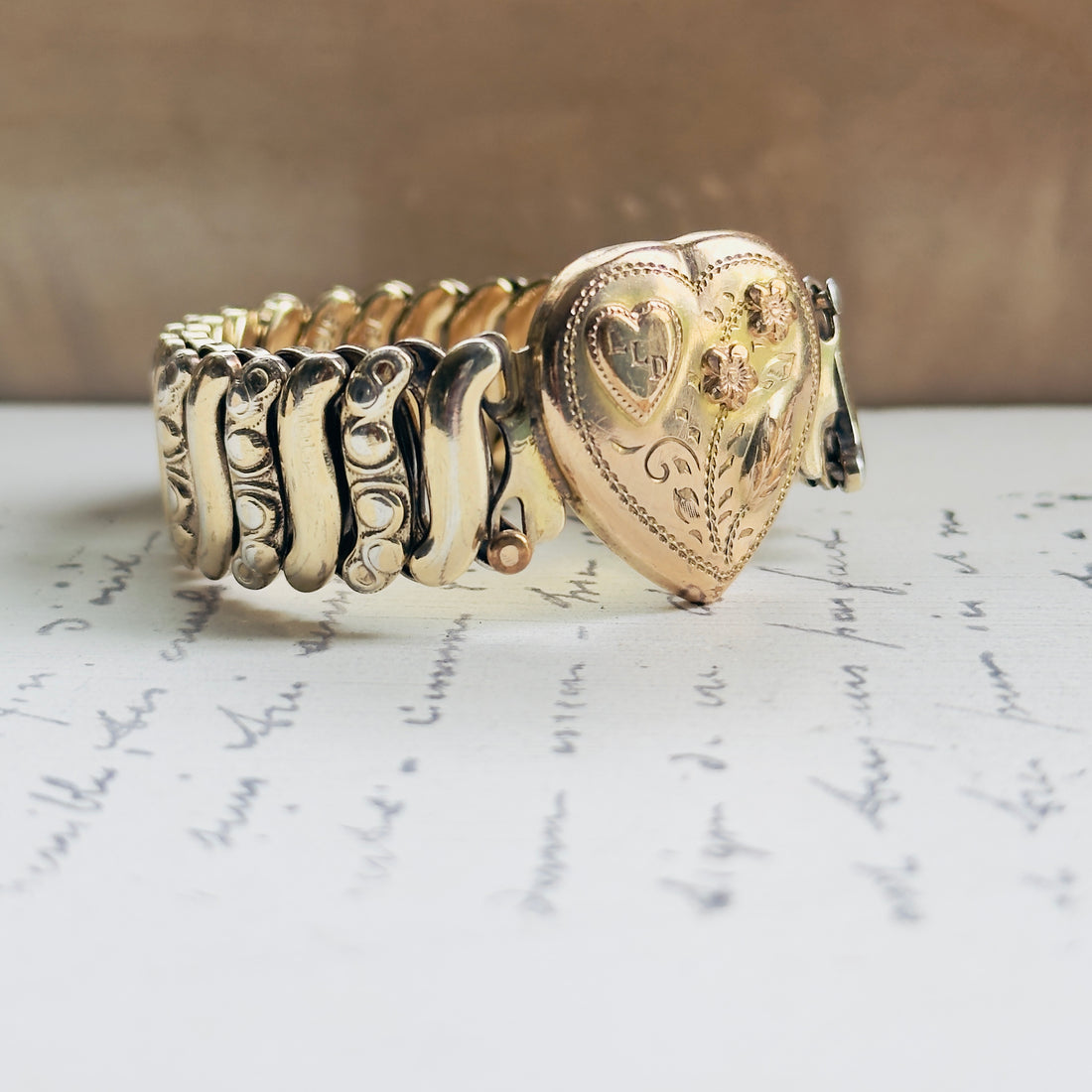 Vintage gold filled sweetheart expansion bracelet by Jewel Guild with scroll-engraved band links, pink enamel florals, and engraved heart center