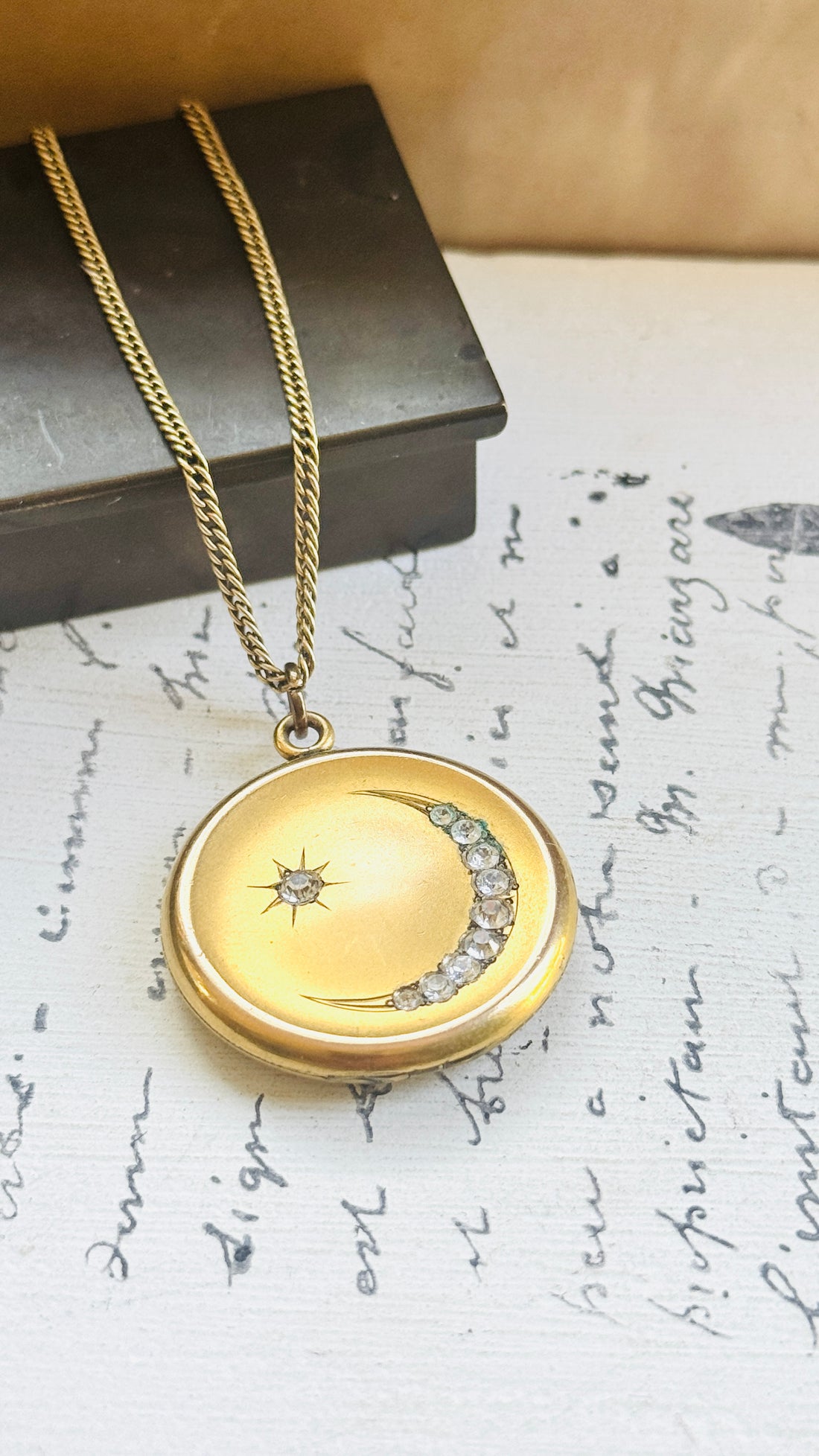 Antique gold filled crescent moon locket with paste stones and star, styled on vintage script paper