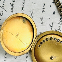 Antique gold filled crescent moon and star locket necklace with paste stones on a white background