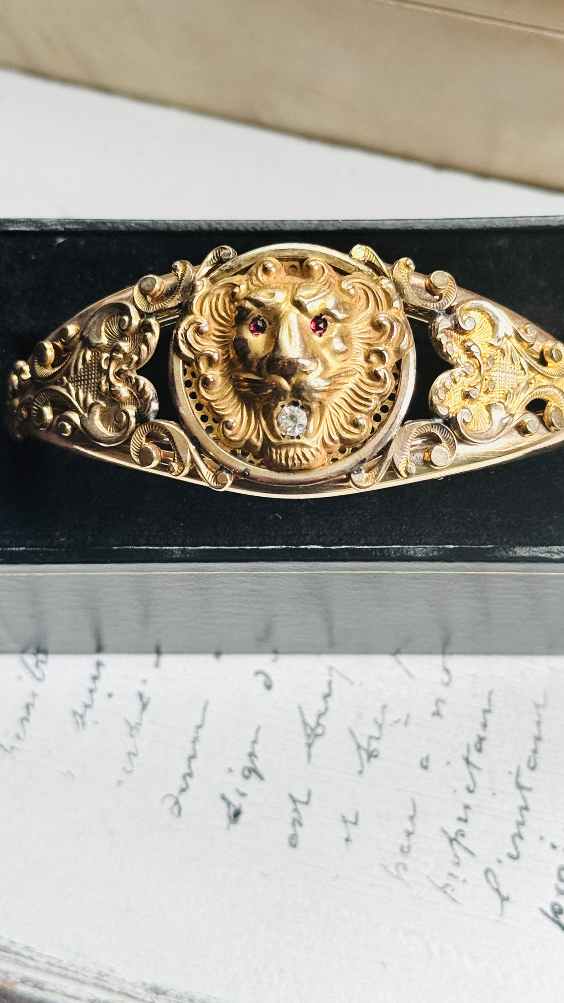 Close-up of the high-relief lion head on an antique gold filled bangle, red paste eyes and clear paste stone in mouth