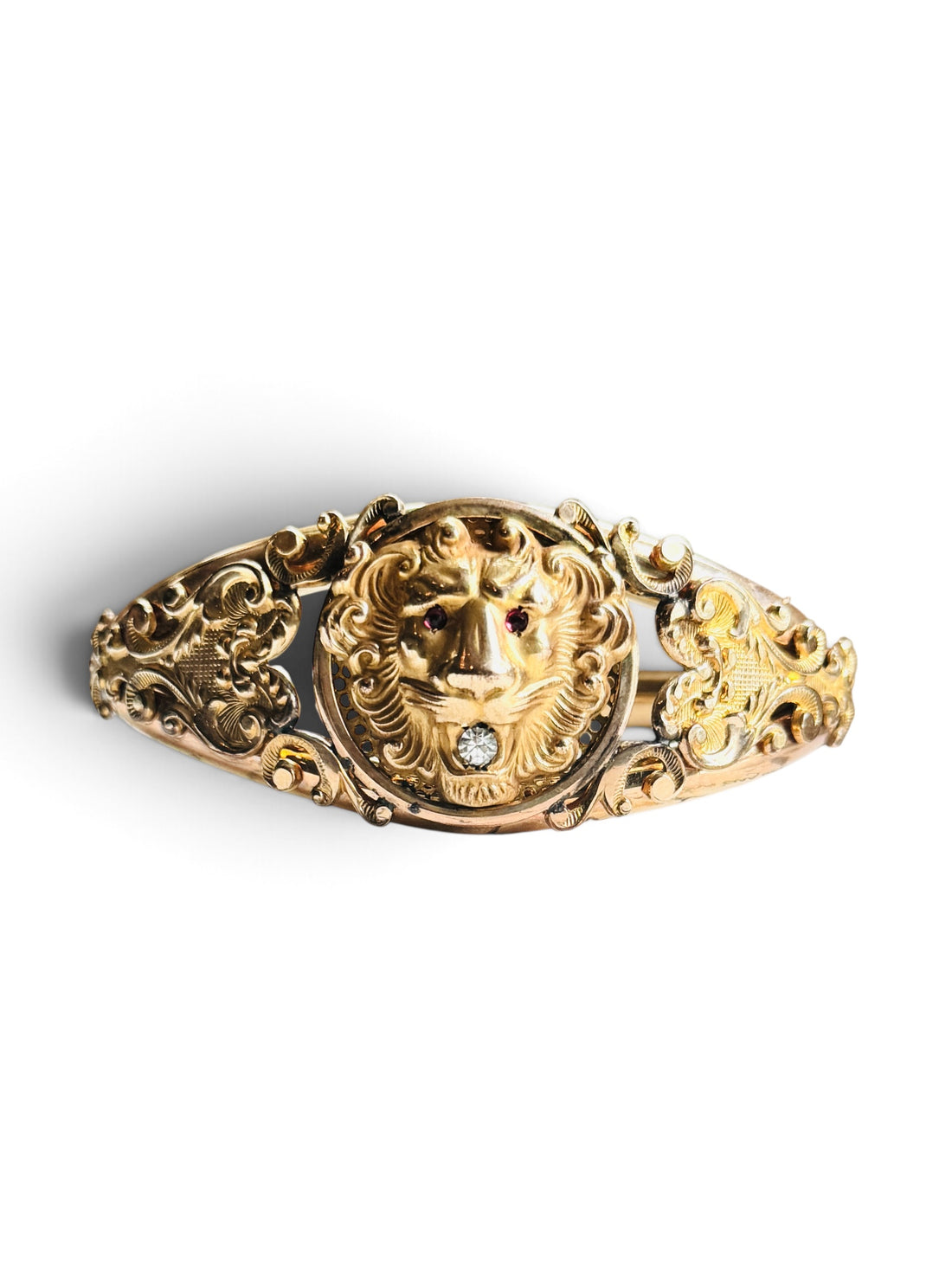 Edwardian gold filled lion head hinged bangle bracelet with red paste eyes and clear paste stone, front view on white
