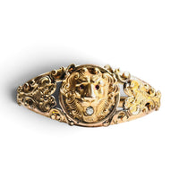 Edwardian gold filled lion head hinged bangle bracelet with red paste eyes and clear paste stone, front view on white