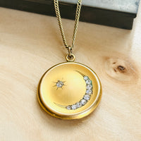 Gold filled crescent moon and star locket hanging from its chain, set with paste stones