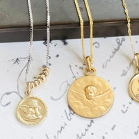 Video featuring a curated collection of antique French pendants, including a Victorian 14k gold cherub pendant alongside two petite French gold pendants.