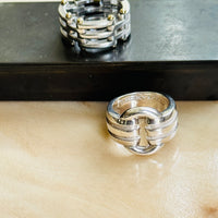 Tiffany Gate Link ring on a dark box with a Tiffany Atlas ring in the foreground