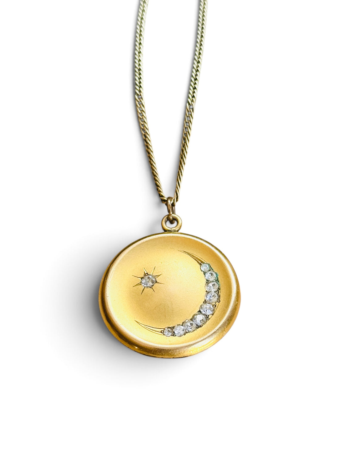 Victorian crescent moon locket shown open, on vintage script paper