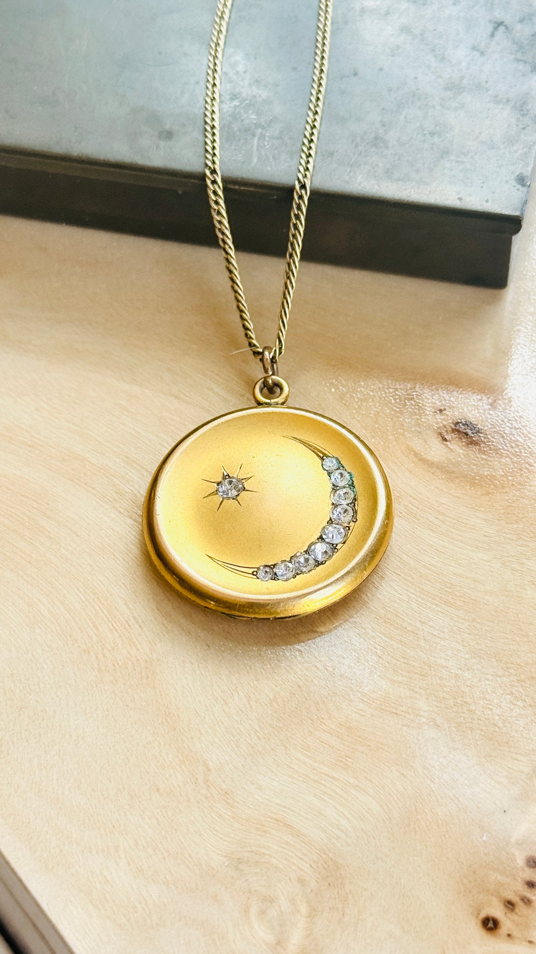 Front of the Victorian crescent moon and star locket with paste stones, on a wooden surface