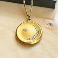 Front of the Victorian crescent moon and star locket with paste stones, on a wooden surface
