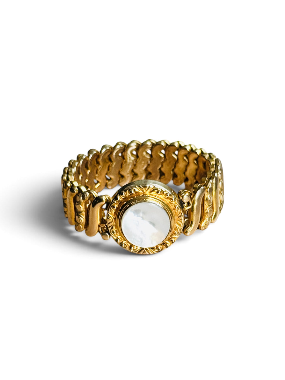 Vintage Gloria gold filled sweetheart expansion bracelet with round white Lucite center, angled view on white