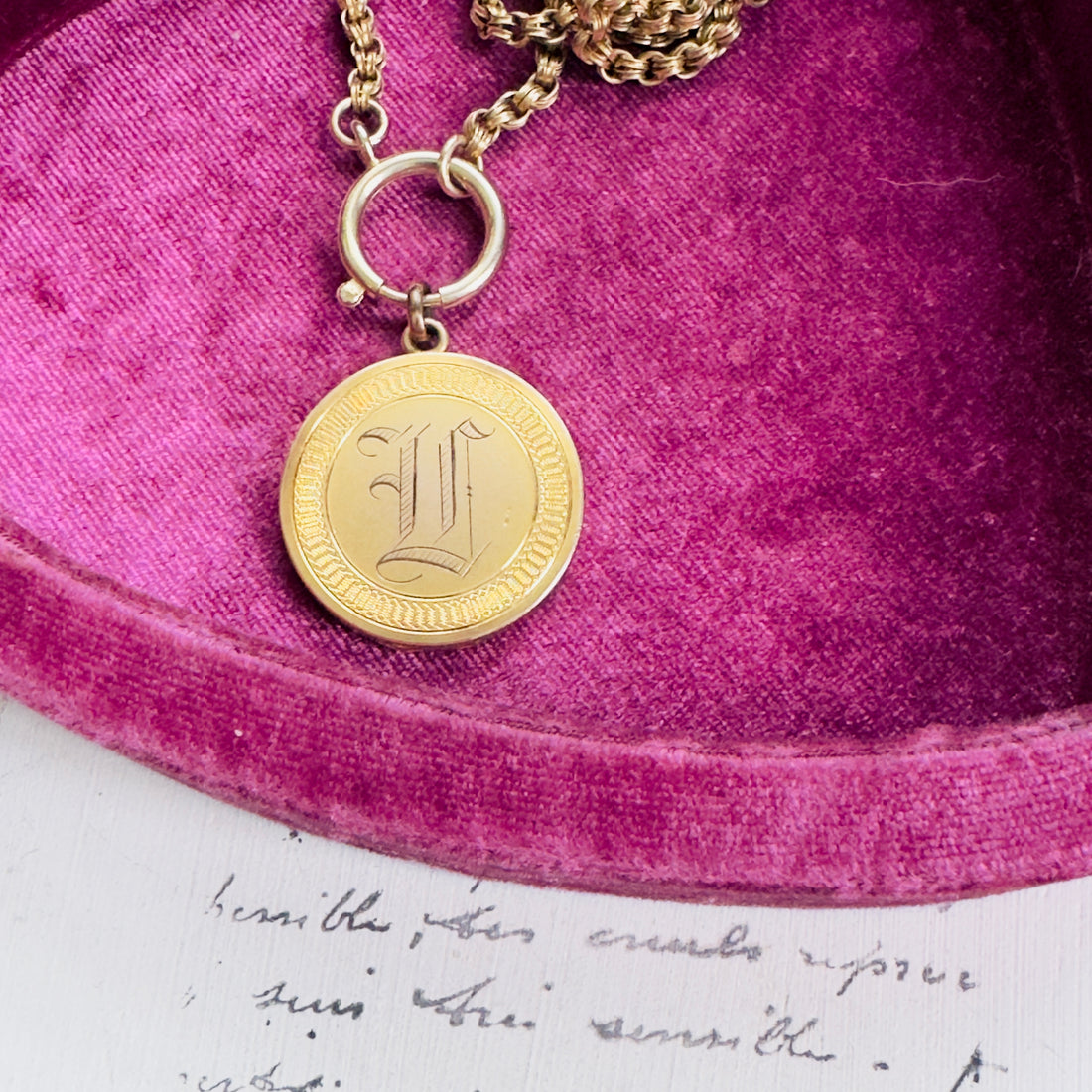Close-up of engraved gold-filled locket showing ornate script detail.